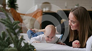 Young mother hugging her newborn child. Mom nursing baby. Woman and new born boy relax in a white bedroom. Family at