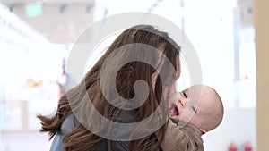 young mother hugging and kissing her infant baby in light background