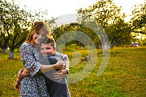 Young mother hugging and kissing her son in summer or autumn park. Family love first. Happy family of mother and child on field at