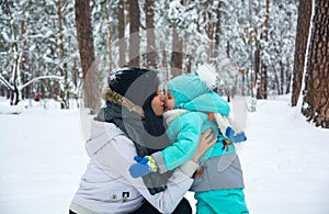 Young mother kisses her baby in the winter park