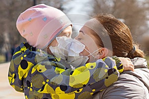 Young mother kisses her daughter through protective medical masks. Covid-19 Coronavirus Pandemic, Virus Protection