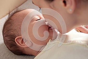 Young mother, kissing her baby boy at home. Family concept. Closeup portrait of loving mother young woman kissing little