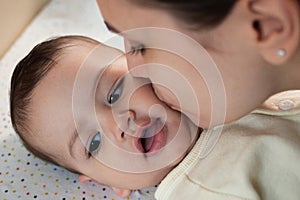 Young mother, kissing her baby boy at home. Family concept. Closeup portrait of loving mother young woman kissing little