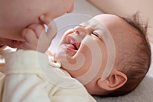 Young mother, kissing her baby boy at home. Family concept. Closeup portrait of loving mother young woman kissing little