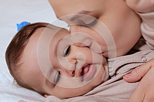 Young mother, kissing her baby boy at home. Family concept. Closeup portrait of loving mother young woman kissing little