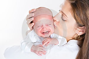 Young mother kissing her crying newborn baby