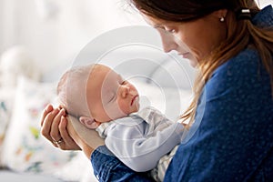 Young mother, kissing her newborn baby boy at home