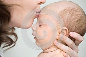 Young mother kissing her newborn baby. Close-up