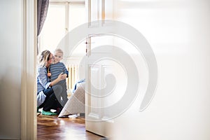 Young mother kissing her toddler son inside in a bedroom. Copy space.