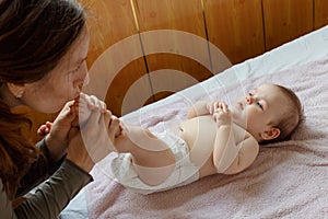 Young mother kissing the tiny feet of her baby