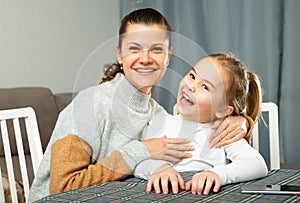 Young mother laughing and tickle her small daughter at sofa