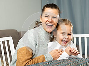 Young mother laughing and tickle her small daughter at sofa