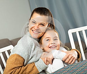 Young mother laughing and tickle her small daughter at sofa