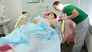 A young mother lies with a newborn in the maternity ward. Relax after childbirth.The happy father kisses her.