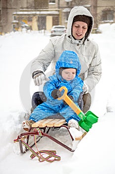 Young mother and little boy enjoying sleigh ride. Child sledding. Toddler kid riding sledge. Children play outdoors in snow. Kids