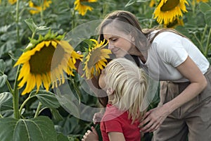 Young mother and little boy are sniffing sunflower. Trusting relationship between son and mother