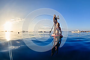 Young mother with little clild paddling on stand up paddleboard