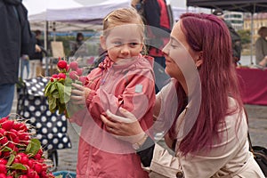 Young mother with little daughter buying fresh radishes