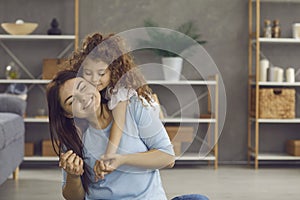 Young mother and little daughter embracing each other, smiling and feeling happy