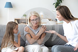 Young mother and little daughter scolding upset grandmother, gen