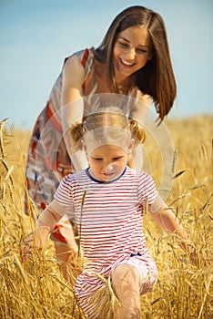 Young mother with little daughter at wheat field