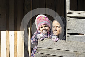 Young mother and a little girl in her hug portrait in wooden hut
