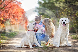 A young mother with a little girl and two dogs on a walk in the Park in autumn