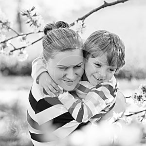 Young mother and little kid boy having fun in blooming garden