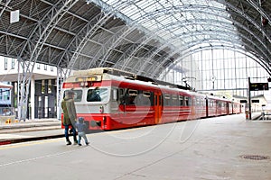 Young mother and little kid walk through the Bergen train station platforms with typical red Voss train on background, Bergen. photo