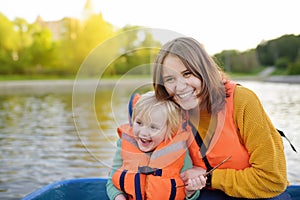 Young mother and little son boating on a river or pond at sunny summer day. Quality family time together on nature photo