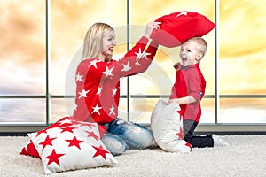 Young mother and little son playing with pillows,pillow fight. The concept of a family holiday.Beautiful pillows to decorate the i