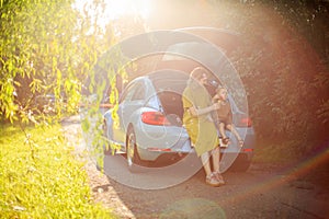 Young mother and little son travelers sit in trunk of car on road and blow soap bubbles. Photo about family travel