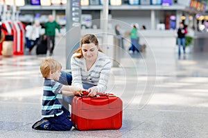 Young mother and little toddler boy son at the airport. Family waiting for flight. Child and woman making vacations by