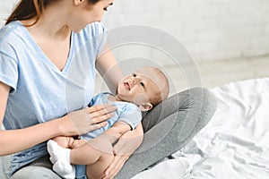 Young mother lulling her adorable baby boy on laps