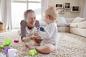 Young mother lying on floor playing with toddler son at home