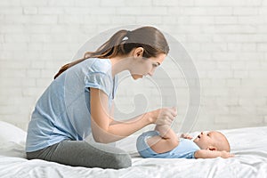 Young mother massaging her newborn baby in bed
