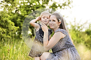 Young mother in nature holding little daughter in the arms.