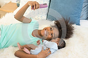 Young mother and newborn baby making video call and smiling greet