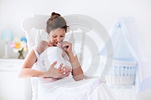 Young mother and newborn baby in white bedroom
