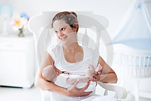 Young mother and newborn baby in white bedroom