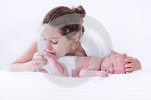 Young mother and newborn baby in white bedroom