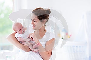 Young mother and newborn baby in white bedroom