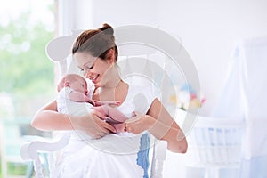 Young mother and newborn baby in white bedroom