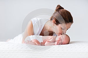 Young mother and newborn baby in white bedroom