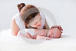 Young mother and newborn baby in white bedroom