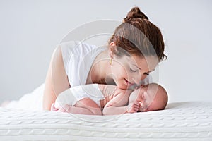 Young mother and newborn baby in white bedroom