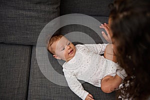 Young mother nursing her adorable smiling baby. First emotions and kids facial expressions in babyhood
