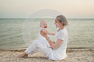 Young mother playing with baby on beach. Vacation with young children at sea