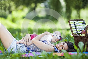 Young mother playing with baby on blanket in the park