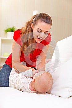 Young mother playing with baby on divan